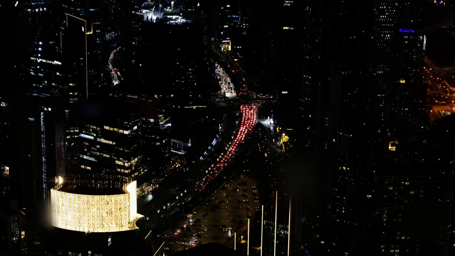 Downtown Dubai at night from above, traffic moving between the towers